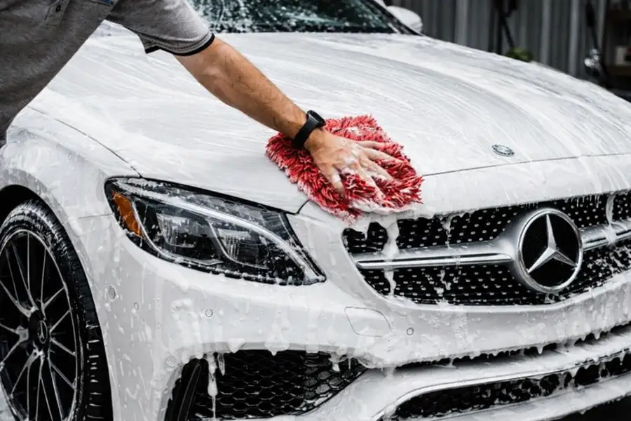 Mobile detailer washing a car in a driveway