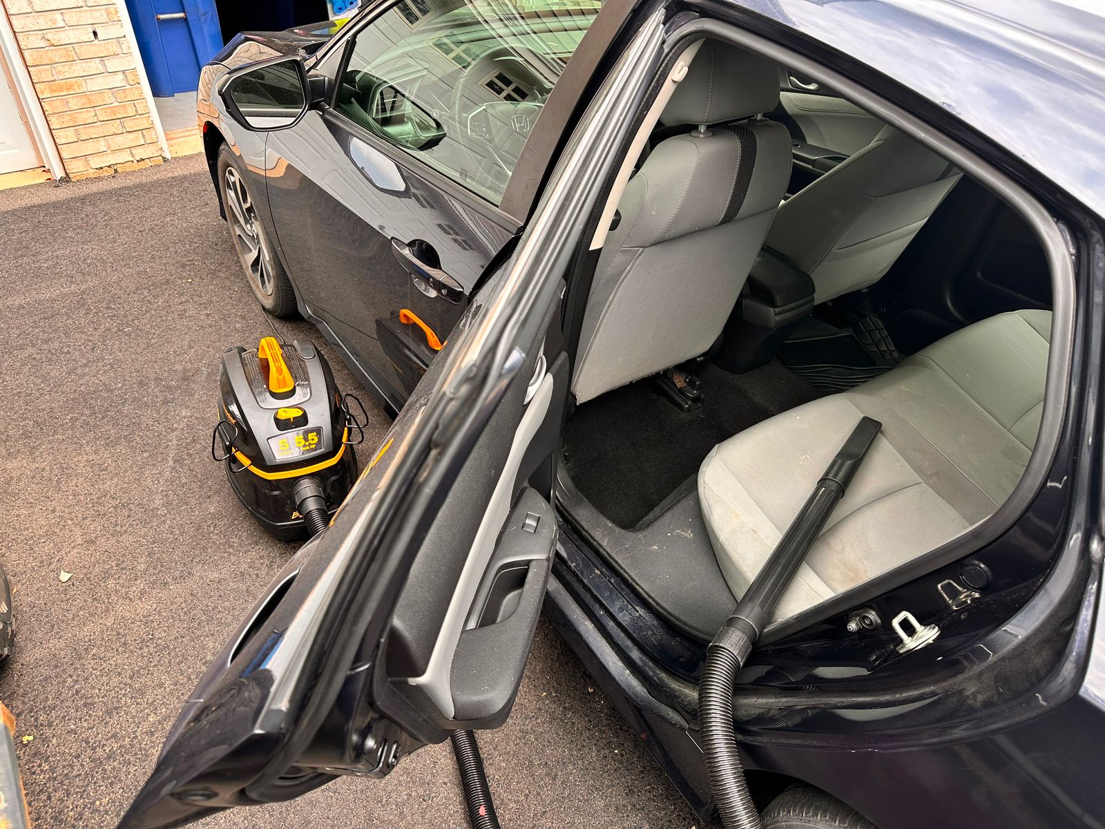 Detail Jockey technician vacuuming a Honda Civic interior — vacuum in use at customer driveway, Flemington NJ mobile detailing