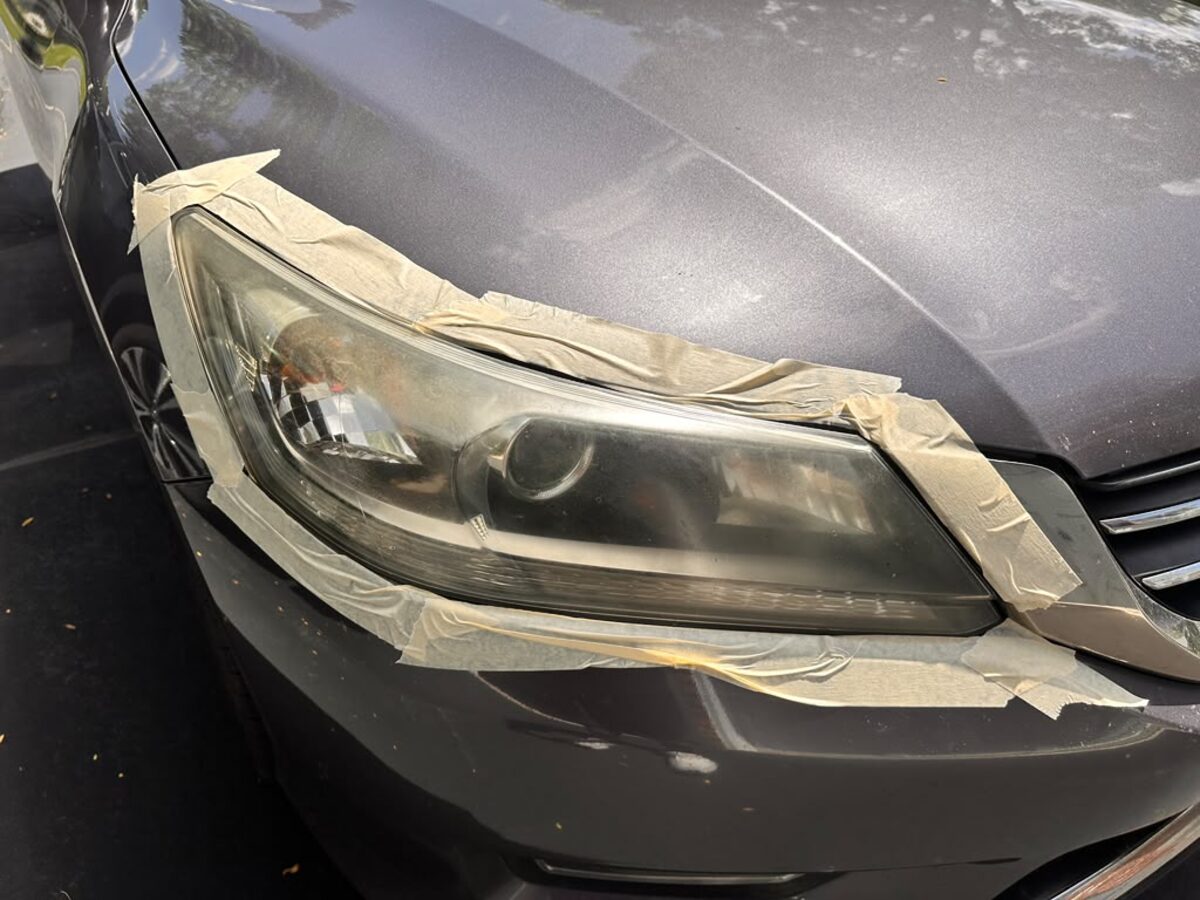 Driver-side headlight before restoration — foggy oxidized lens with masking tape, Honda Accord Flemington NJ